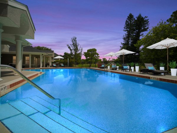 Sparkling, resort-style pool and expansive sundeck with lounge chairs at sunset